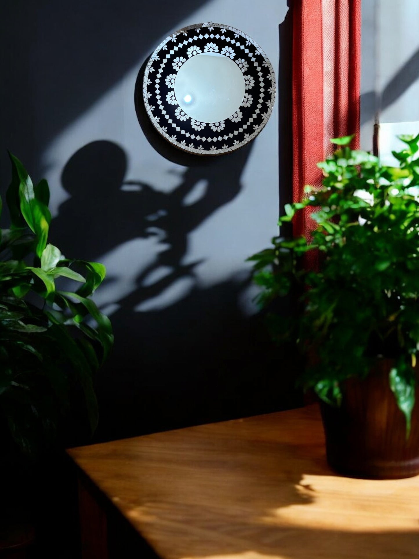 Angled view of black floral mosaic mirror reflecting bulb