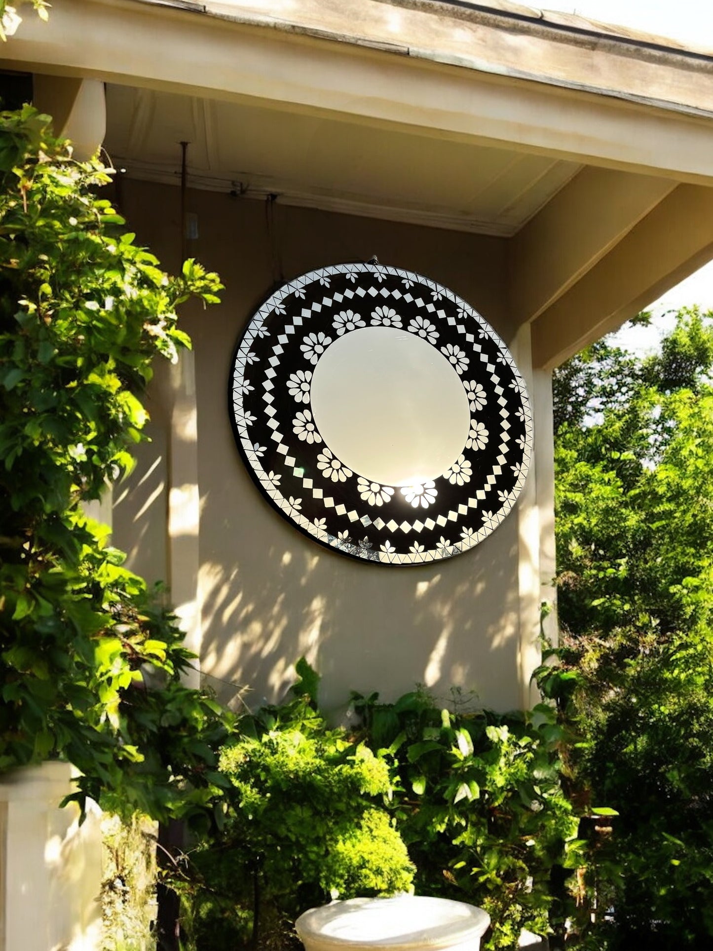 Handcrafted round mosaic mirror by Mirroza displayed in a modern patio setting, adding elegance and artistic charm to outdoor decor.