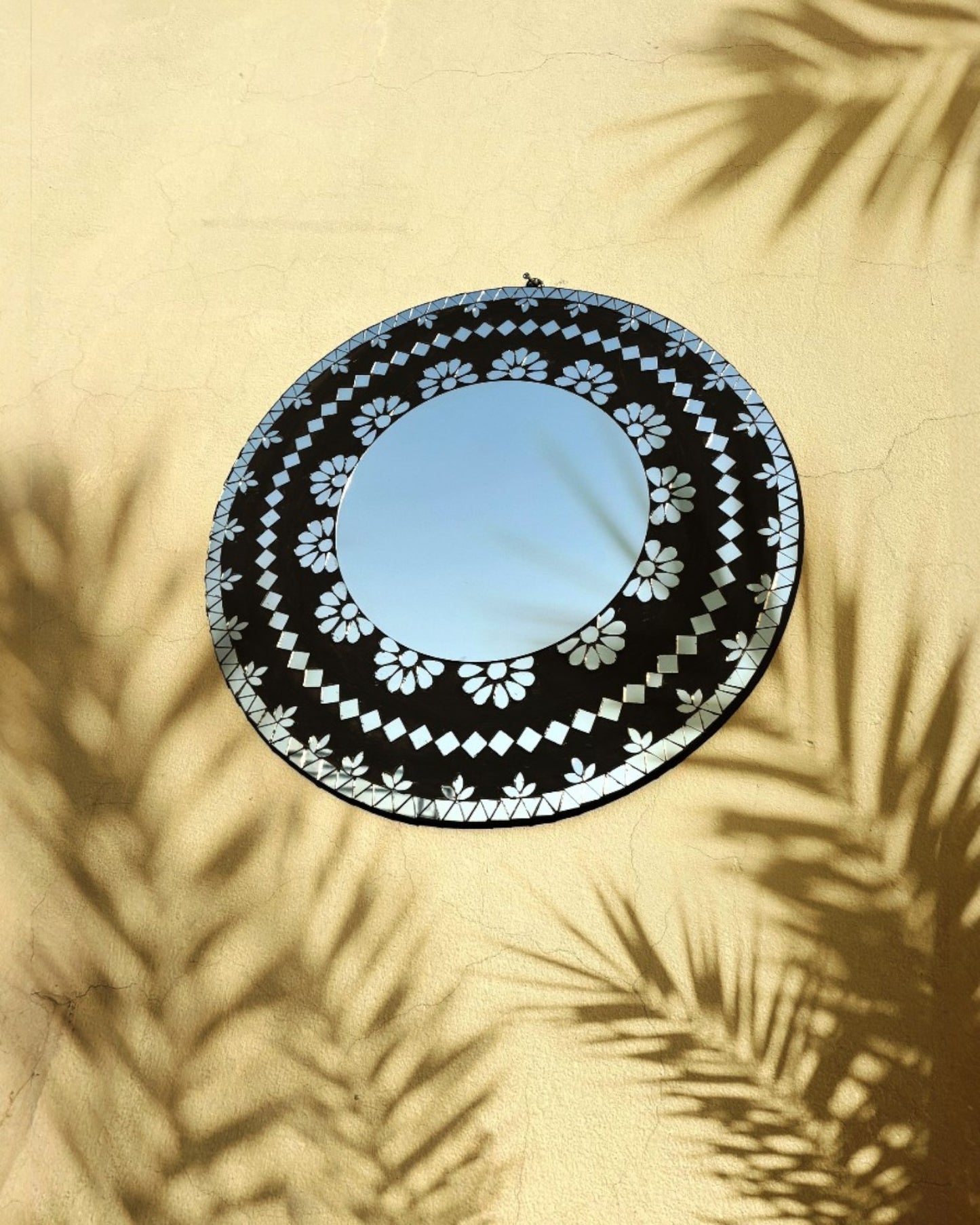 Handcrafted mosaic mirror catching natural light and creating reflections