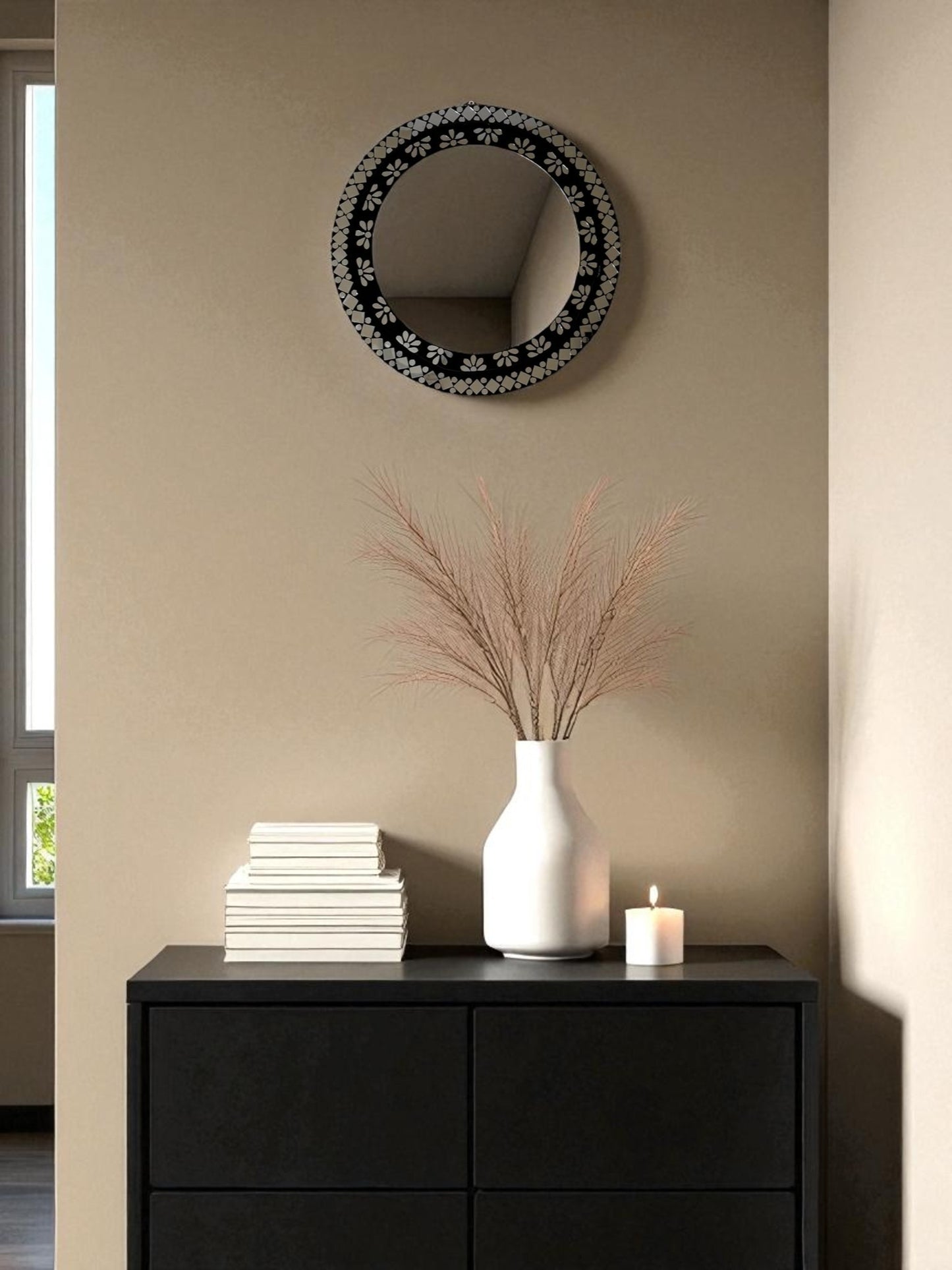 Black floral round mosaic mirror displayed above a minimalist console table in a clean and modern interior setting.