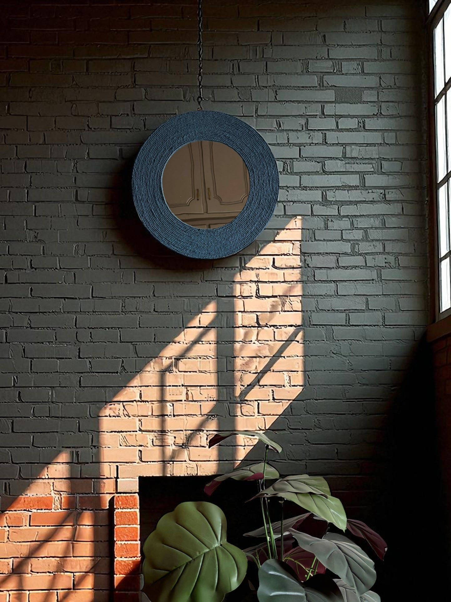 Muted blue rope mirror wall art mounted on a dark brick wall creating bold contrast