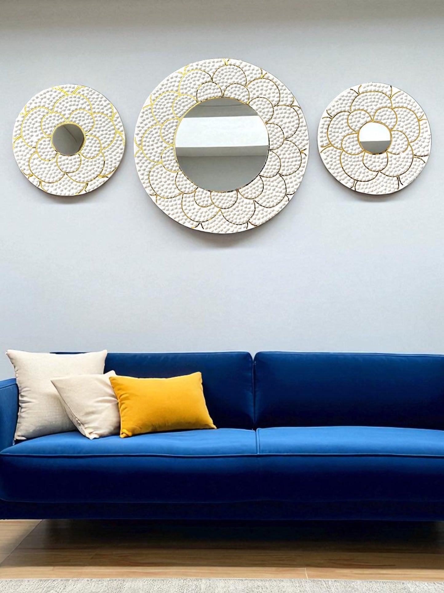 White and gold mirror mosaic wall art set displayed above a deep navy blue velvet sofa on a beige living room wall
