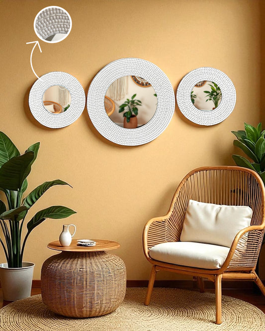 Boho-inspired corner featuring ivory round mirror mosaic wall art on a textured beige wall, surrounded by rattan furniture, macramé, and lush indoor plants like monstera and snake plan