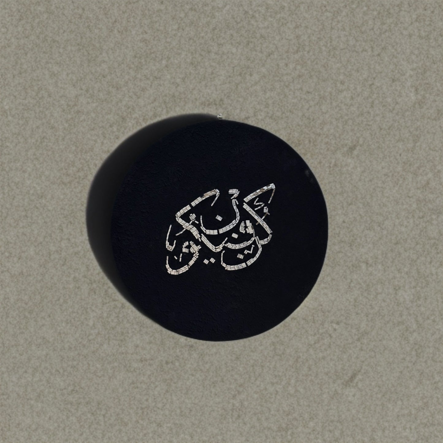 Kun Fayakun mosaic mirror calligraphy piece displayed on a concrete wall