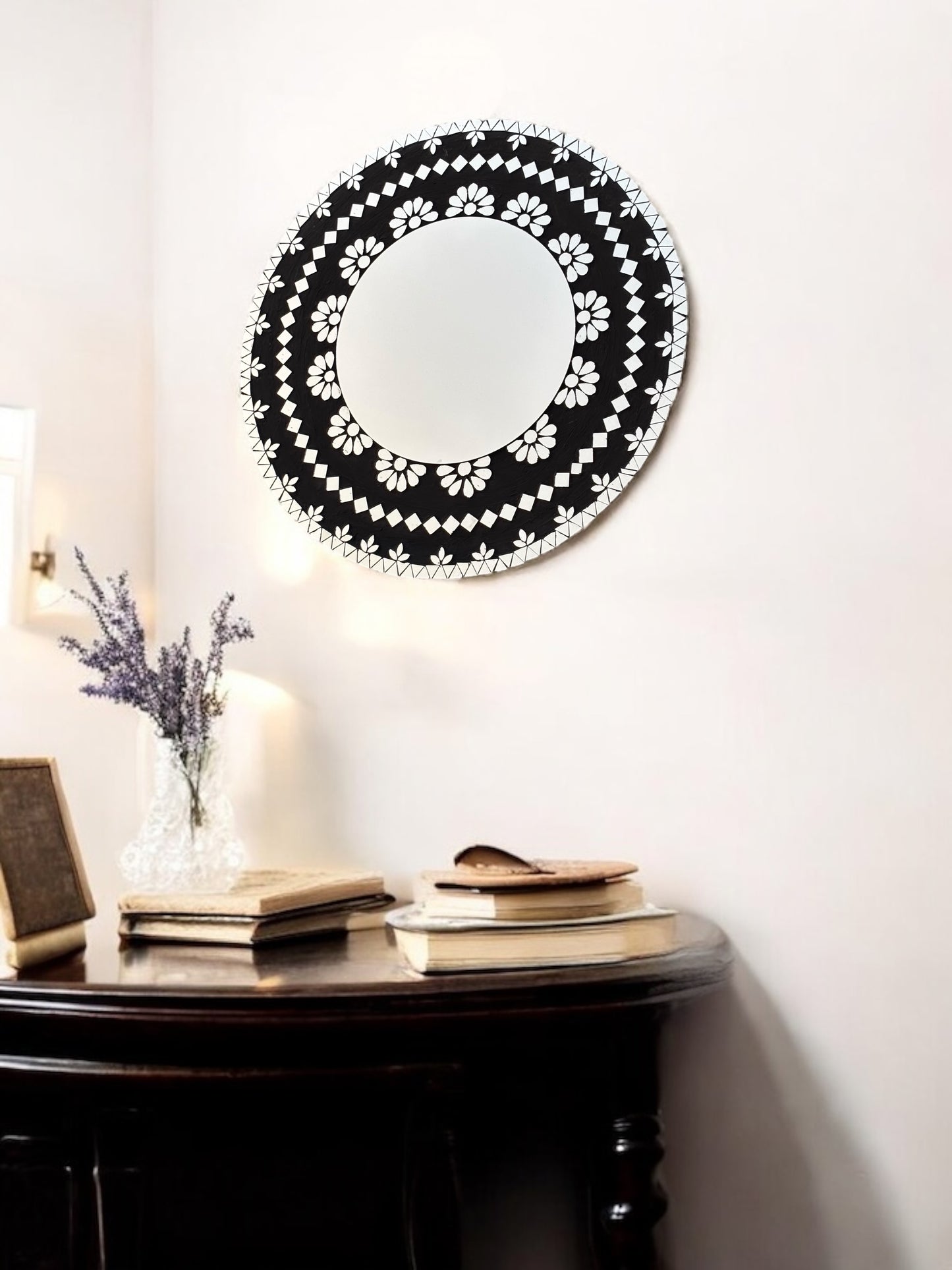 Mirroza black bloom round mosaic mirror with black and white pattern on a wall above a dark wooden console table.