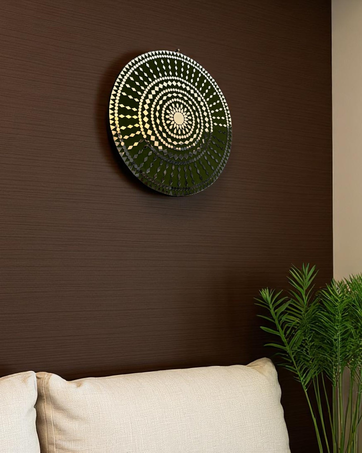 Right angle view of handcrafted Olive Bloom round mosaic wall mirror reflecting light on its intricate glass inlay on dark wooden wall