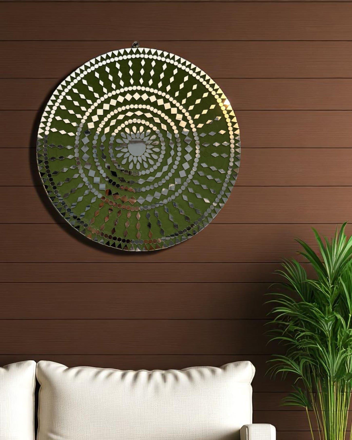 Close up angle view of handcrafted Olive Bloom round mosaic wall mirror reflecting light on its intricate glass inlay on a dark wooden wall with white sofa