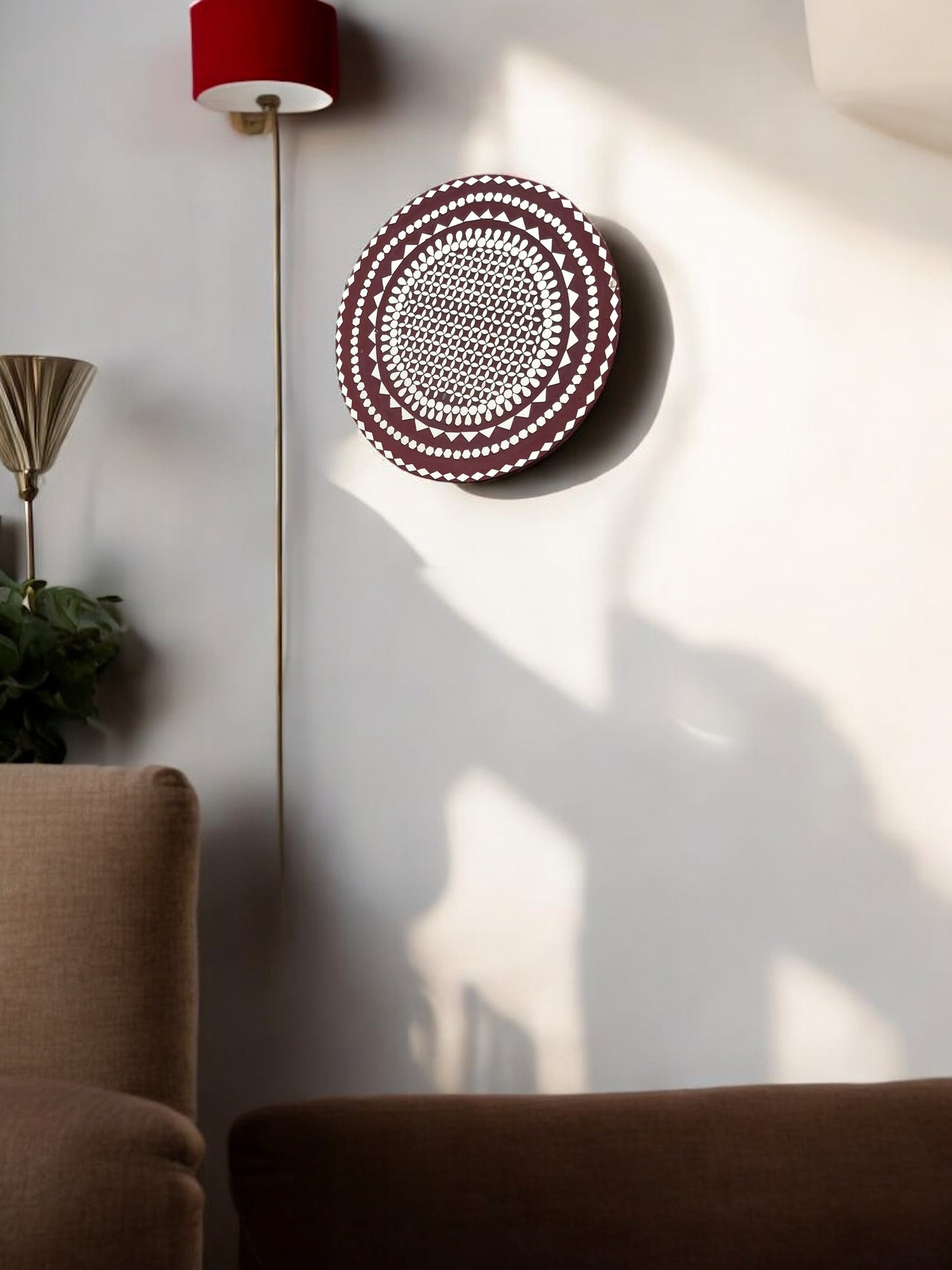 Handcrafted raspberry mosaic wall mirror in a sunlit corner with plants and neutral decor.