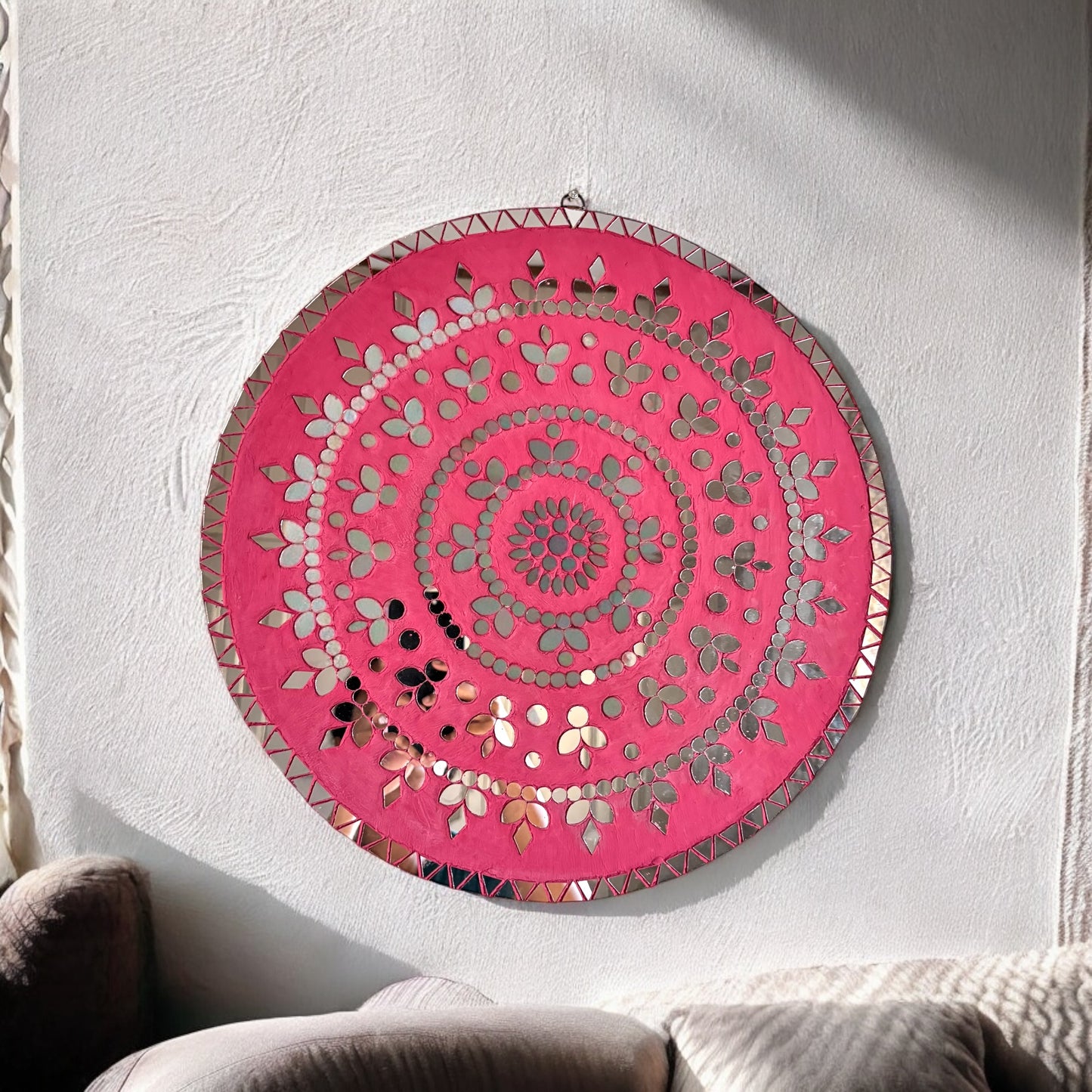 Round rose gold mosaic wall art with mirror petals and geometric border, hanging on a white textured wall.