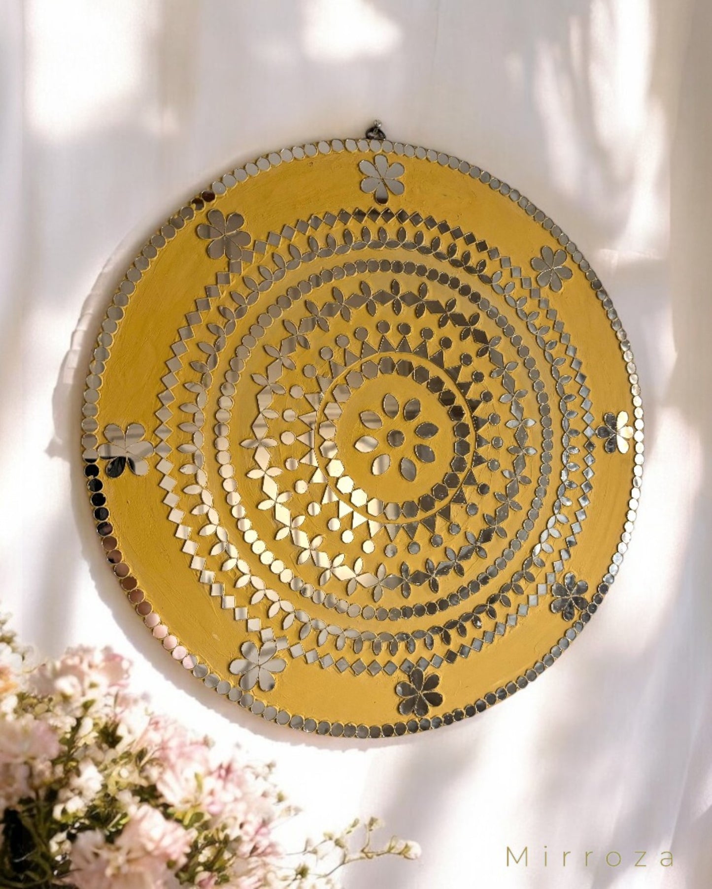 Yellow floral round mirror wall art in sunlit setting with flowers in foreground, boho home decor