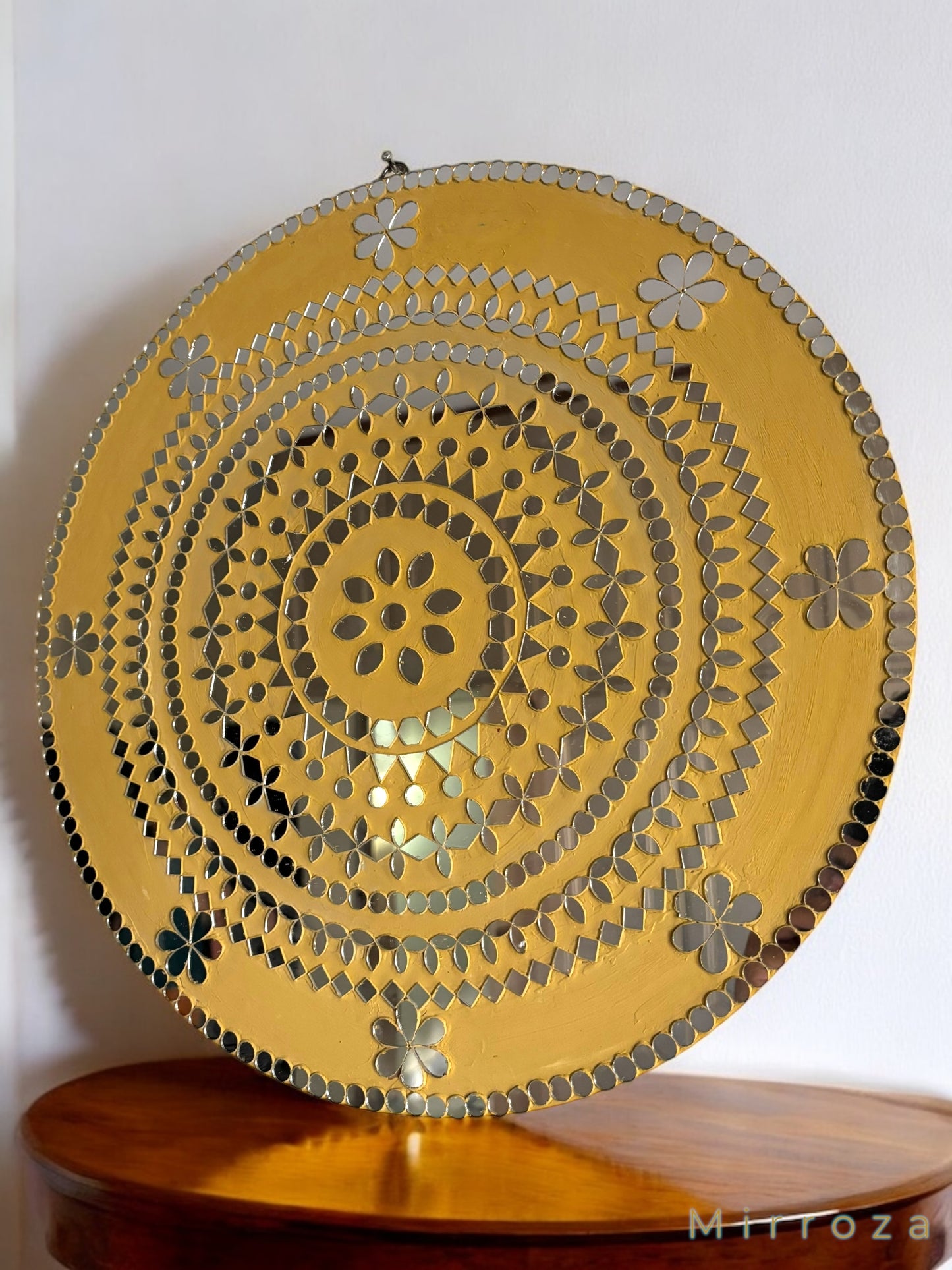 Yellow floral round wall mirror styled above a green console table in a modern entryway with rug and vase decor