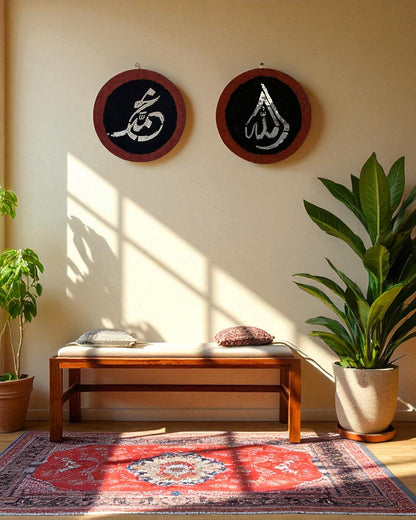 Welcoming entryway with round mosaic Islamic calligraphy art of Allah and Muhammad, paired with indoor plants and a wooden bench under natural light.