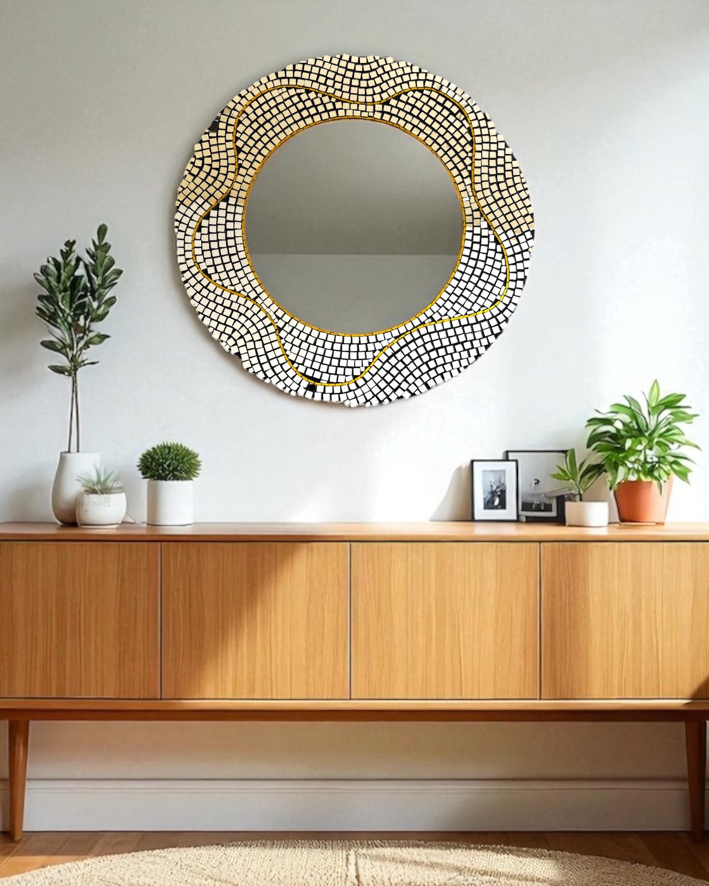 Round decorative mirror mosaic with a gold frame on a wall above a wooden console table.