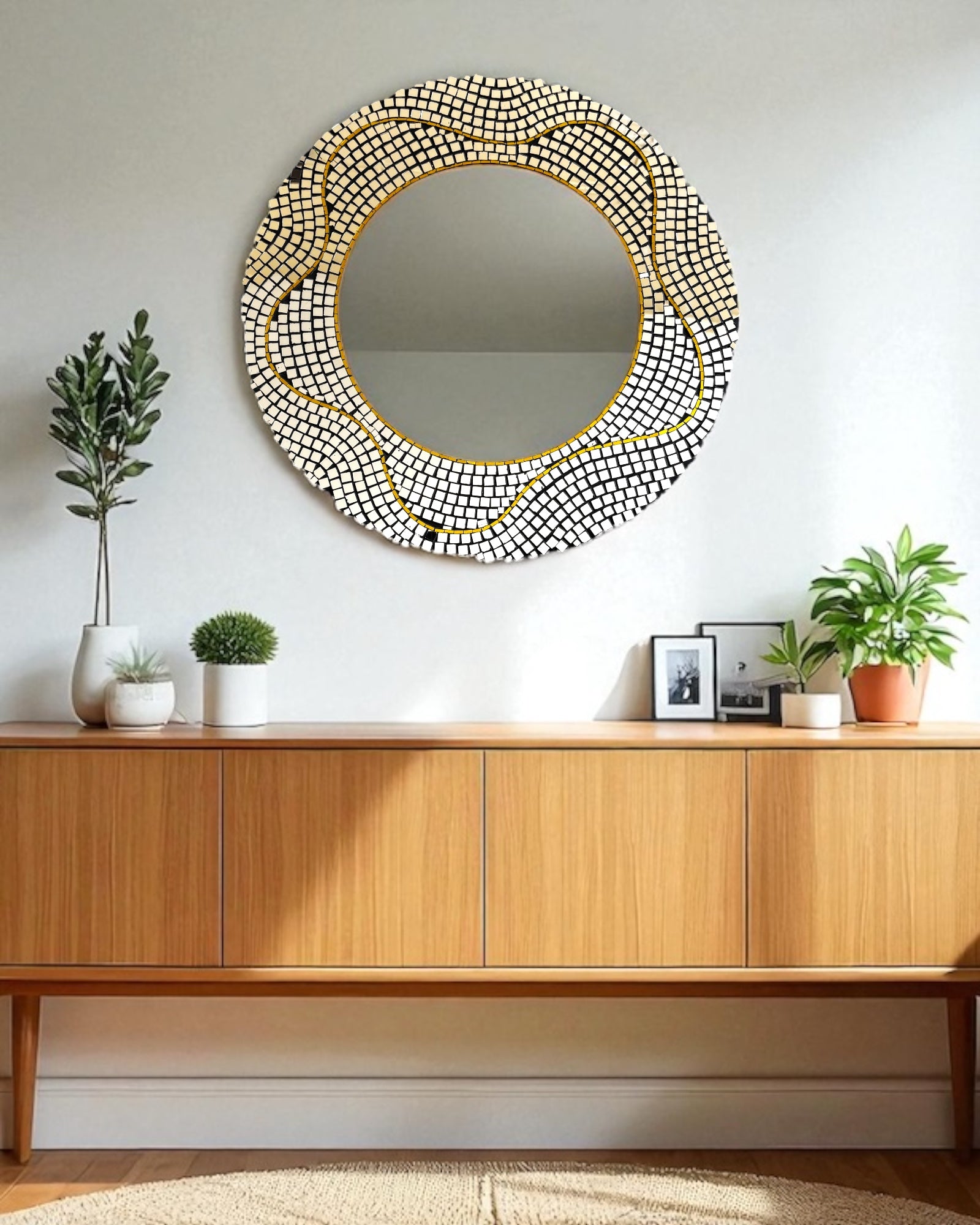 Round decorative mirror mosaic with a gold frame on a wall above a wooden console table.