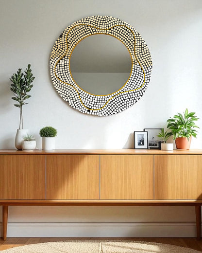 Round decorative mirror mosaic with a gold frame on a wall above a wooden console table.