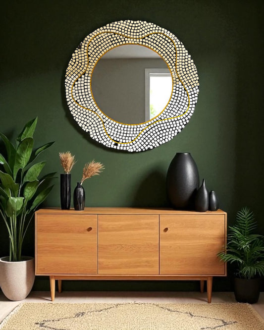 round mosaic mirror with a beaded frame on a green wall above a wooden console table.