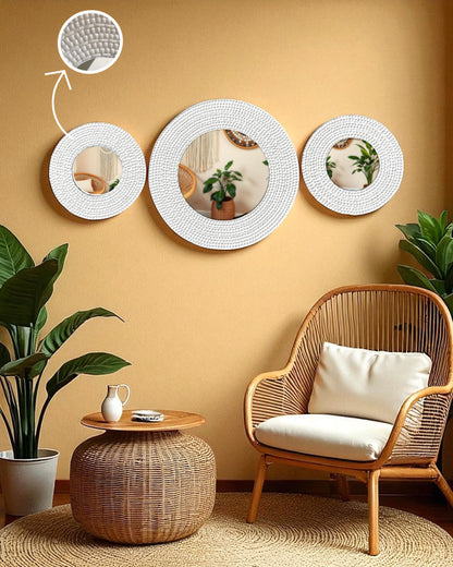 Boho-inspired corner featuring ivory round mirror mosaic wall art on a textured beige wall, surrounded by rattan furniture, macramé, and lush indoor plants like monstera and snake plan