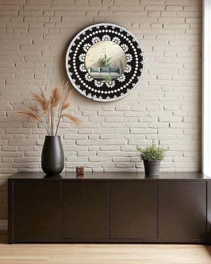 Mirroza black bloom mosaic mirror with floral design on a wall above a dark wooden cabinet.