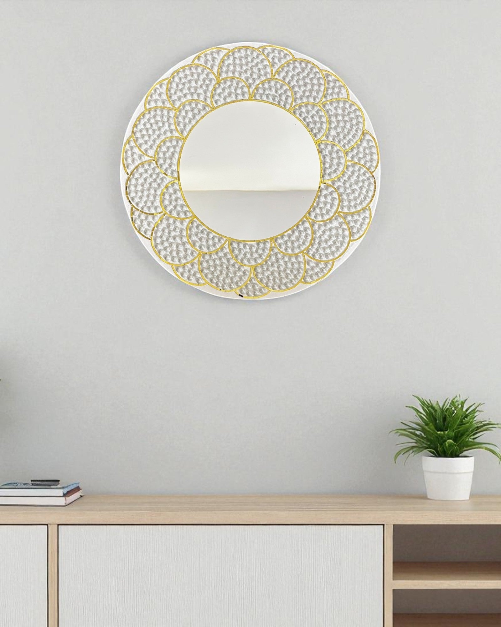 Decorative wall mirror with gold frame on a light gray wall above a wooden console table.